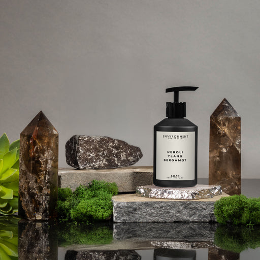 Black soap dispenser labeled 'Envisionment' on a stone platform with a gray background