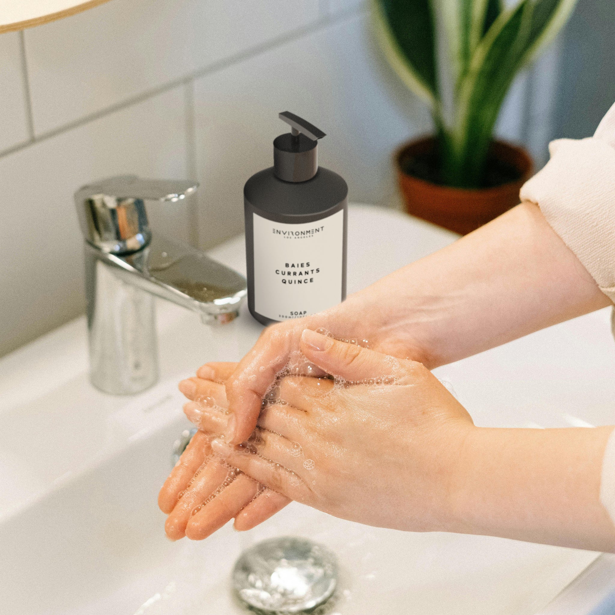 A woman washing her hands with a Baies hand soap 