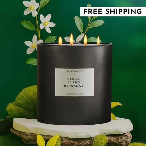 Black candle labeled 'Neroli Ylang Bergamot' with floral elements on a green background