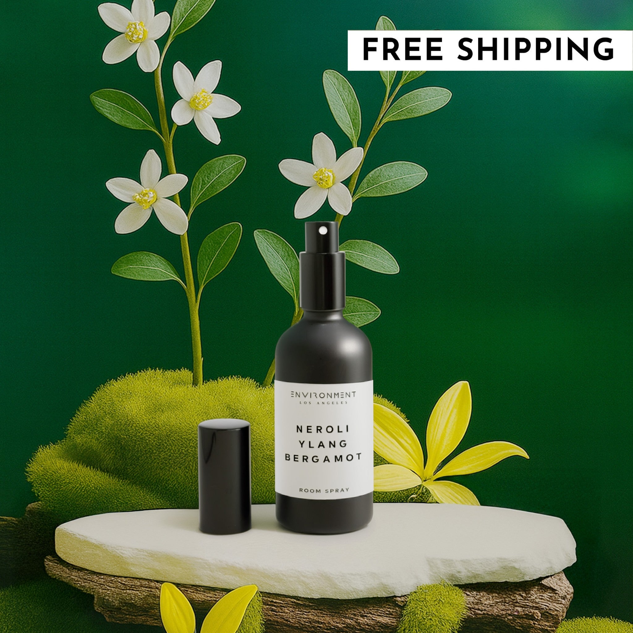 Black room spray bottle with white label on a green background with flowers and moss