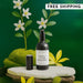 Black room spray bottle with white label on a green background with flowers and moss