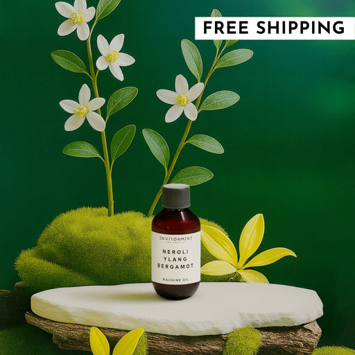 Bottle of 'Neroli Ylang Bergamot' oil with flowers and greenery on a dark green background